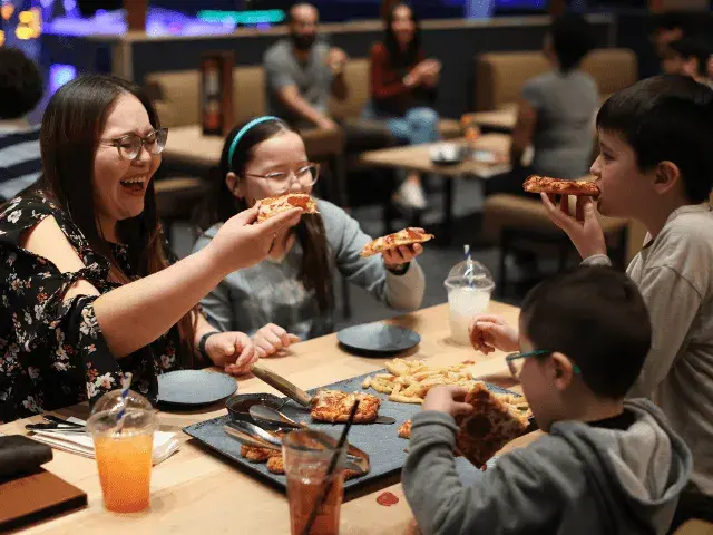 A family eating pizza in a Splitsville Bowl centre