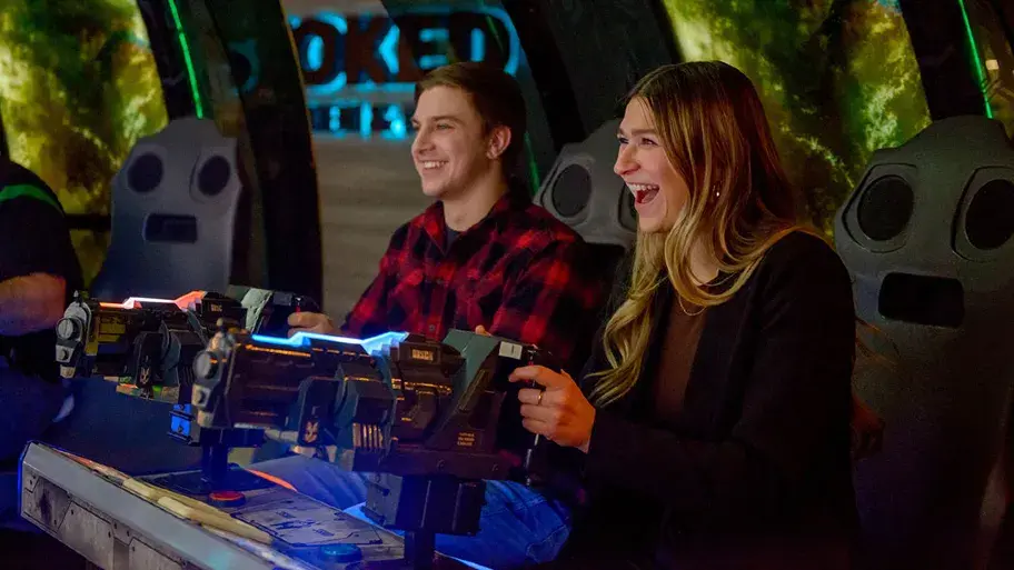 A couple having fun on a shooting game in the arcade at Stoked in Saskatoon