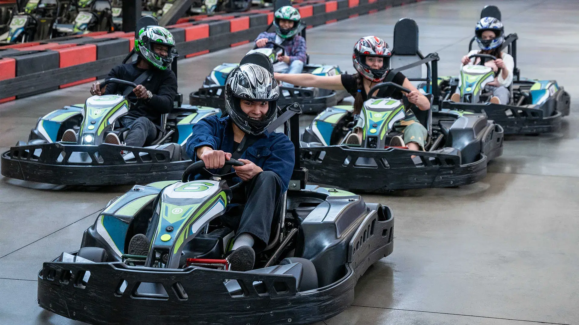 A group of people racing go-karts at Stoked Saskatoon, showcasing excitement and competition among the participants.