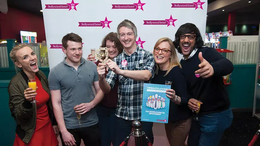 Group of adults posing with King pin trophy