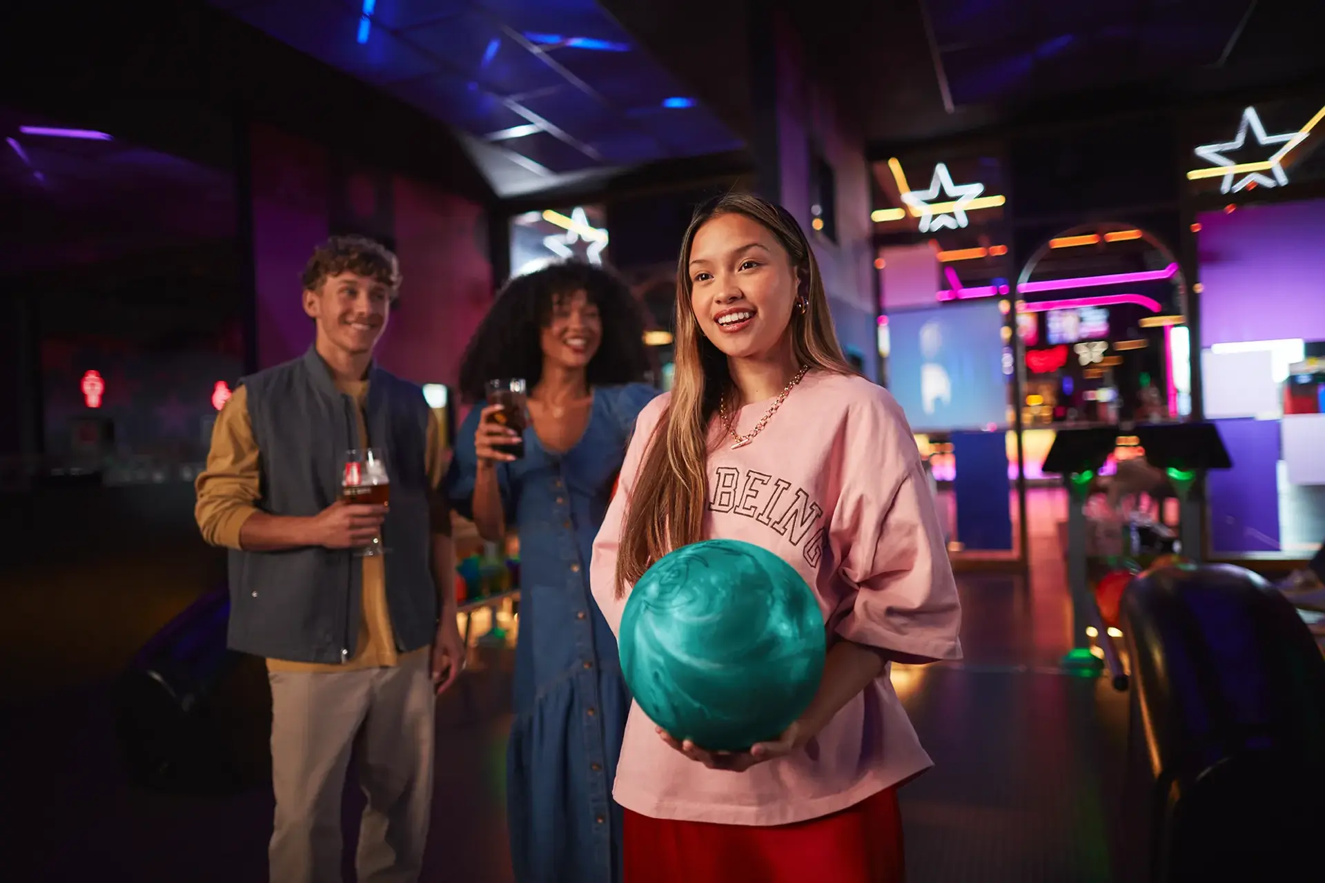 A group of friends standing together in a lively bowling alley, smiling and enjoying their time.