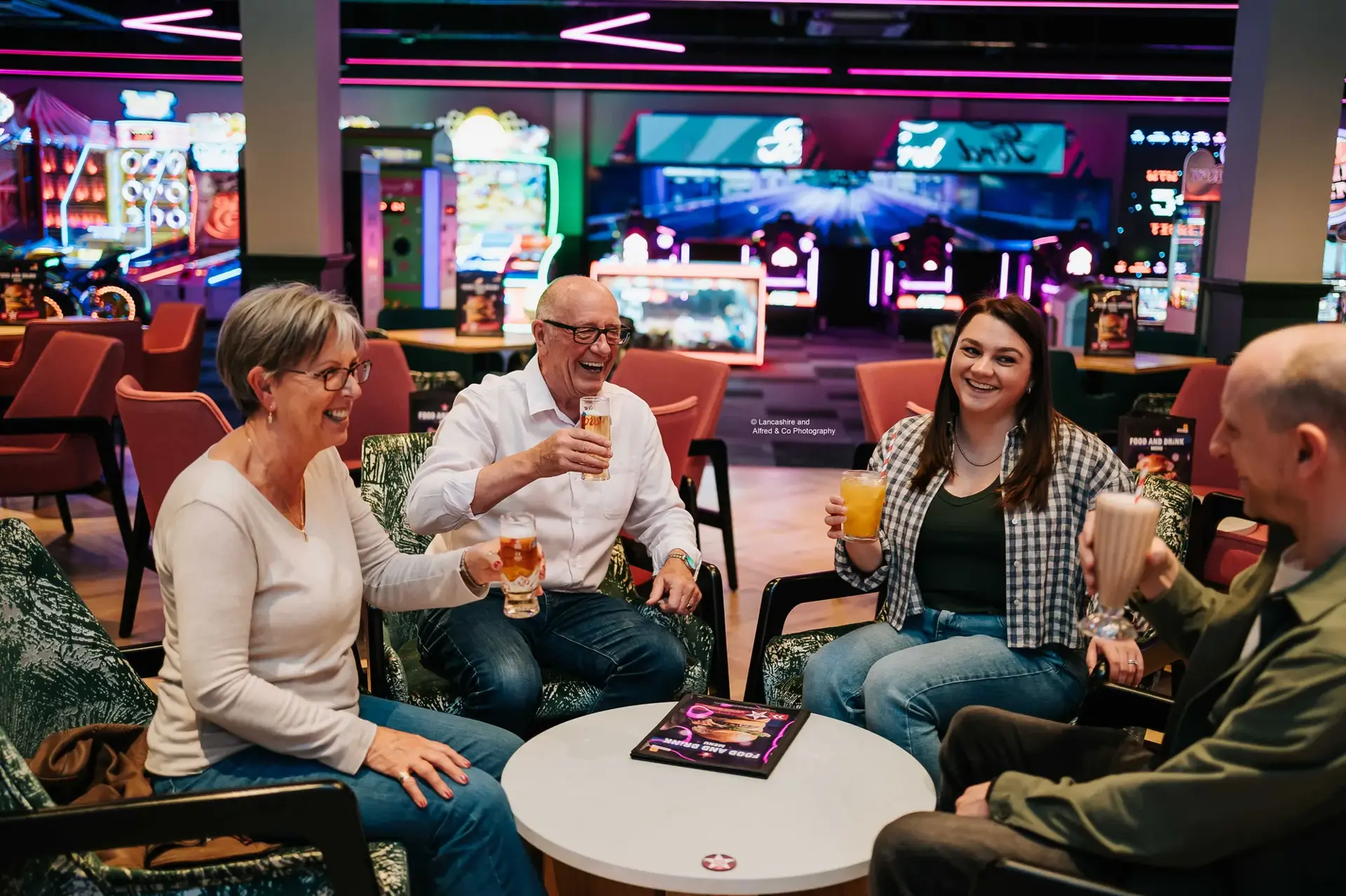 Four people enjoying a drink at a table in Hollywood Bowl Preston.