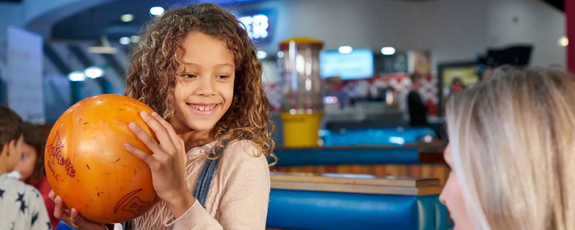 Young girl getting ready to bowl with family