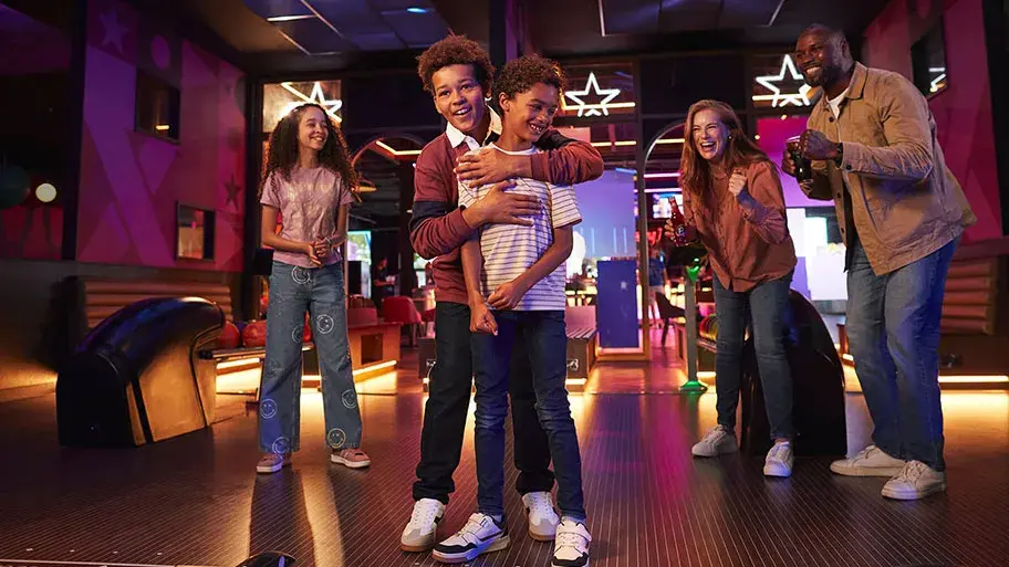 A joyful family enjoys bowling together, laughing and cheering at the bowling alley