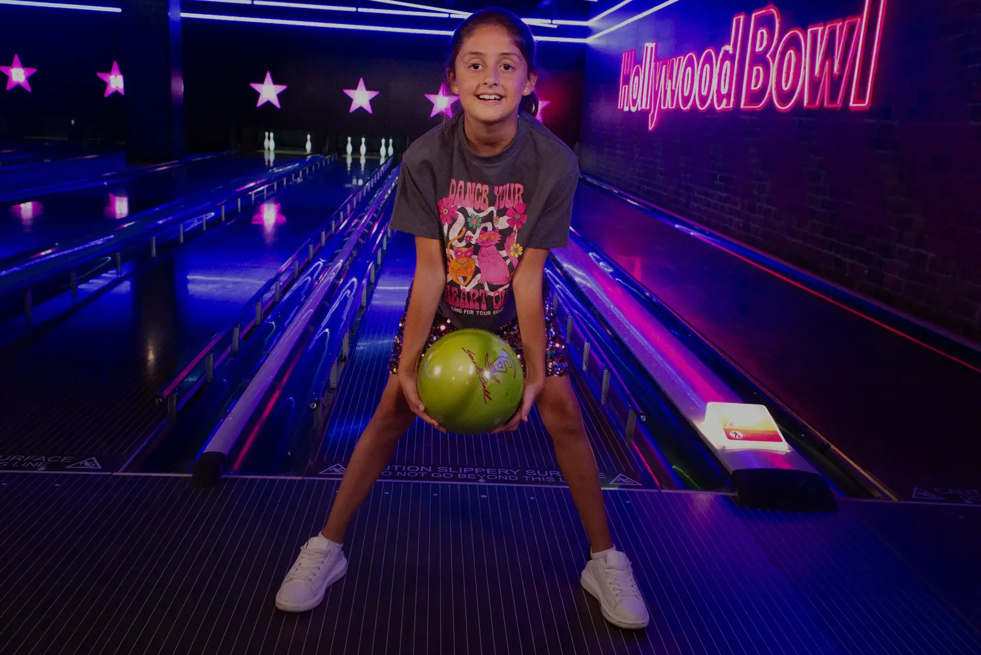 A girl holding a green bowling ball at Hollywood Bowl