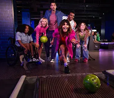 A group of people joyfully toasting with drinks at a Hollywood Bowl, celebrating together in a lively atmosphere.