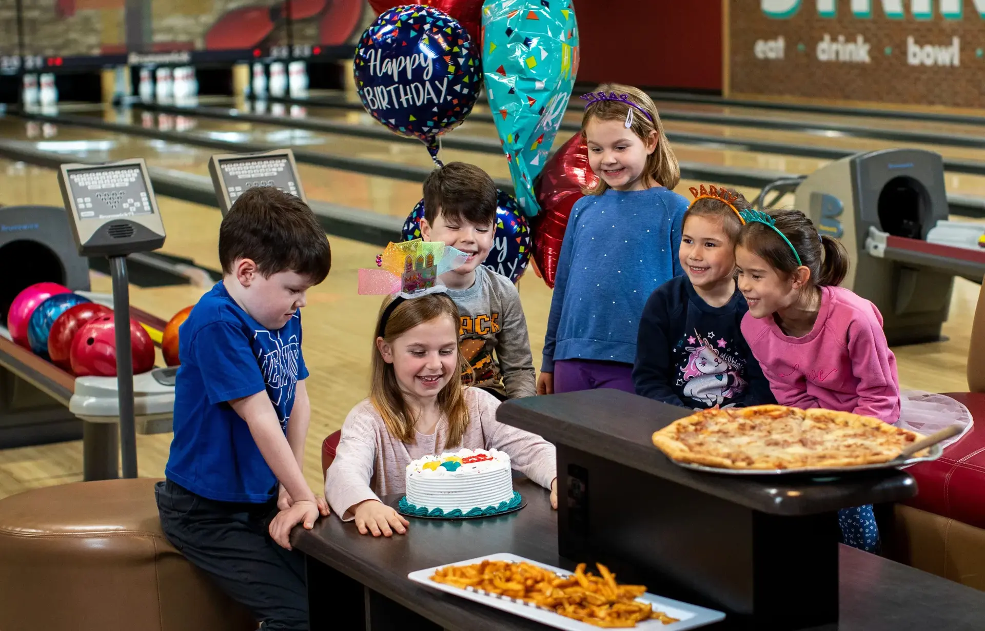 Children celebrating a birthday party with a cake and food at Stoked