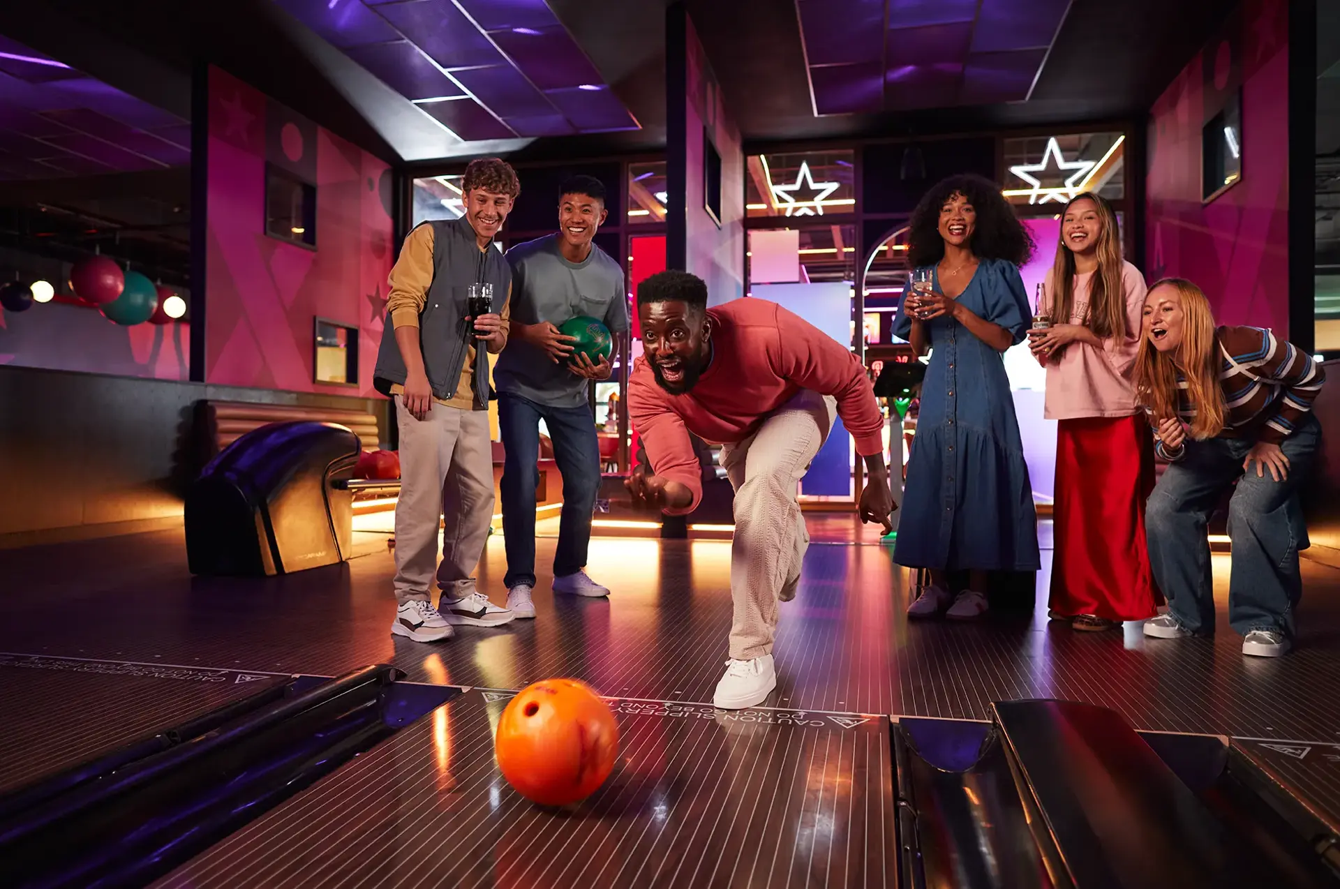 A lively group of friends enjoying a fun bowling night at the alley, laughing and celebrating their strikes.