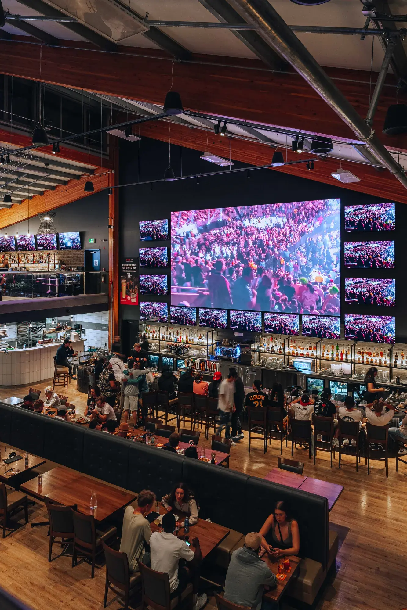 The lively sports bar at Stoked Bar & Grill, featuring large screens and customers enjoying drinks and games together.