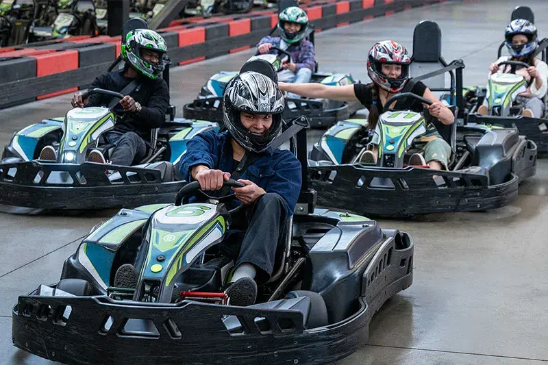 A group of people racing go-karts at Stoked Saskatoon, showcasing excitement and competition on the track.