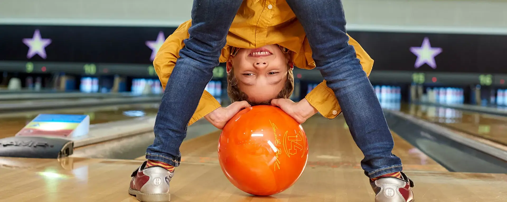 Young boy peering over bowling ball cheekily