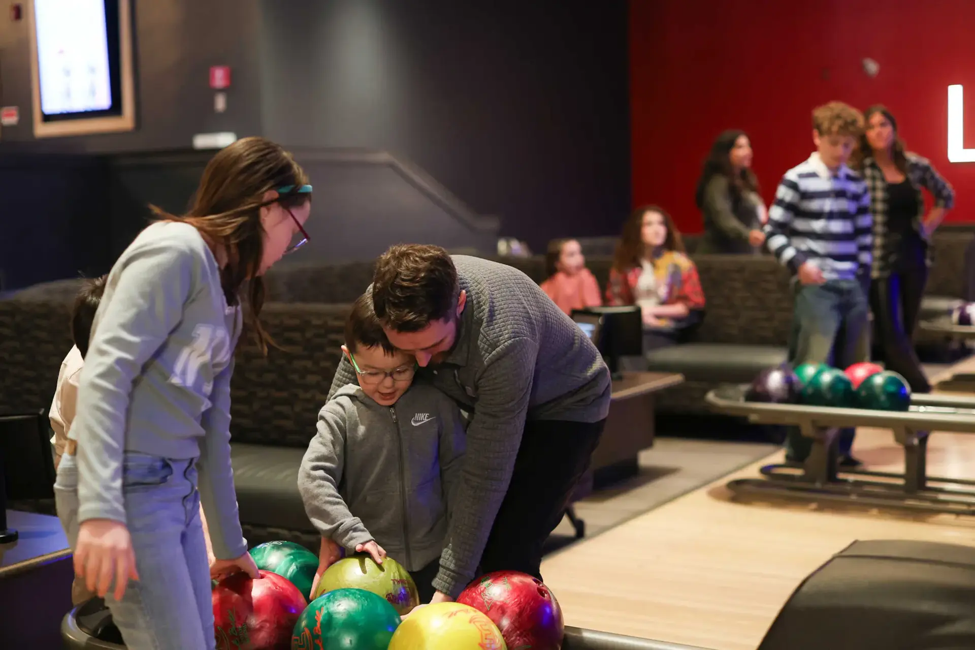 A family enjoying a fun bowling game together at a local bowling alley, smiling and cheering each other on.